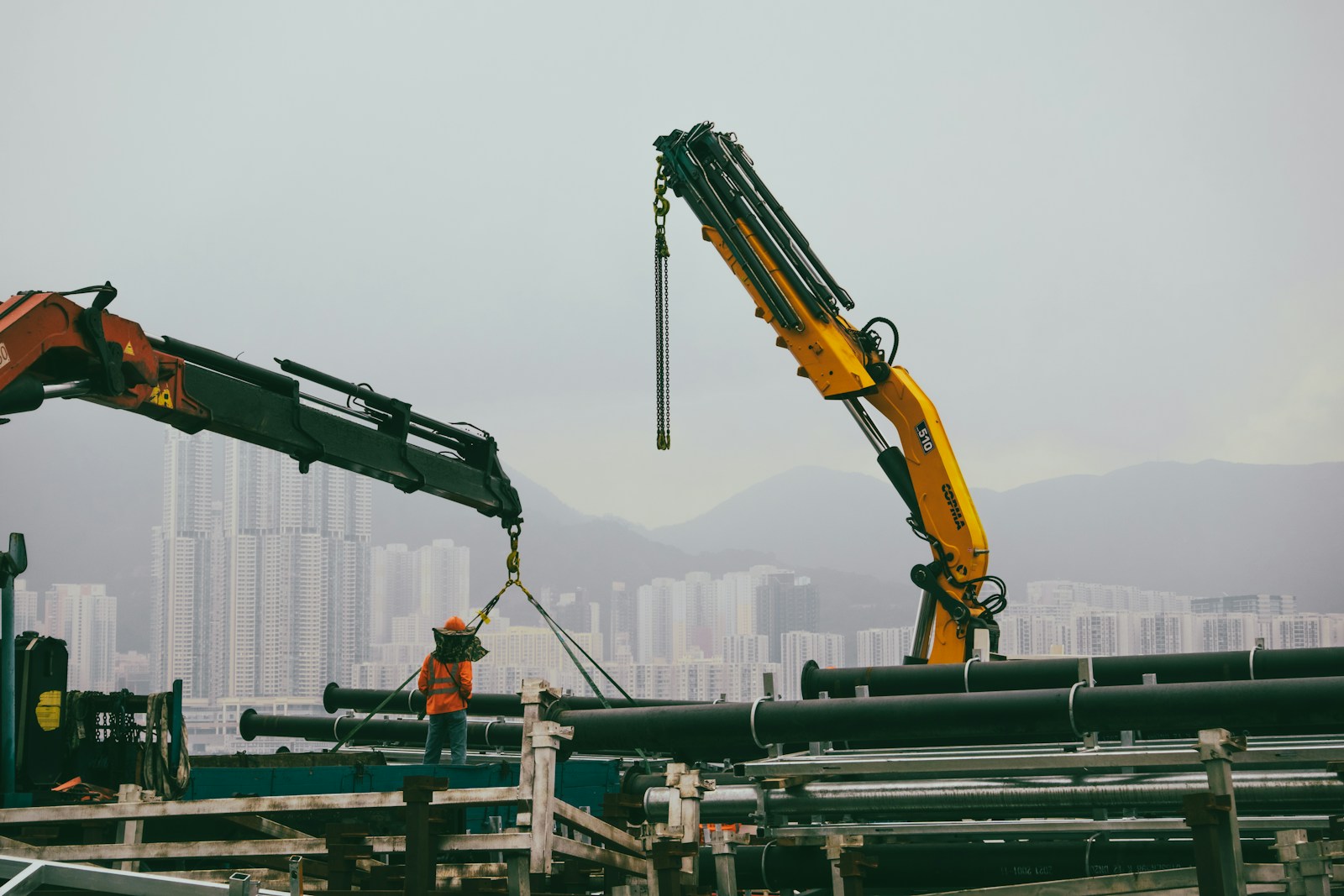 A crane is lifting pipes into the air