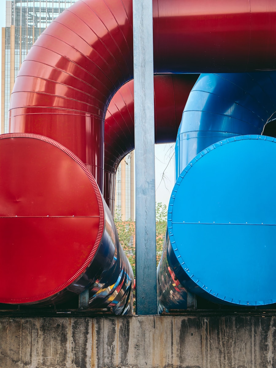 a large red and blue pipe sitting on top of a cement wall